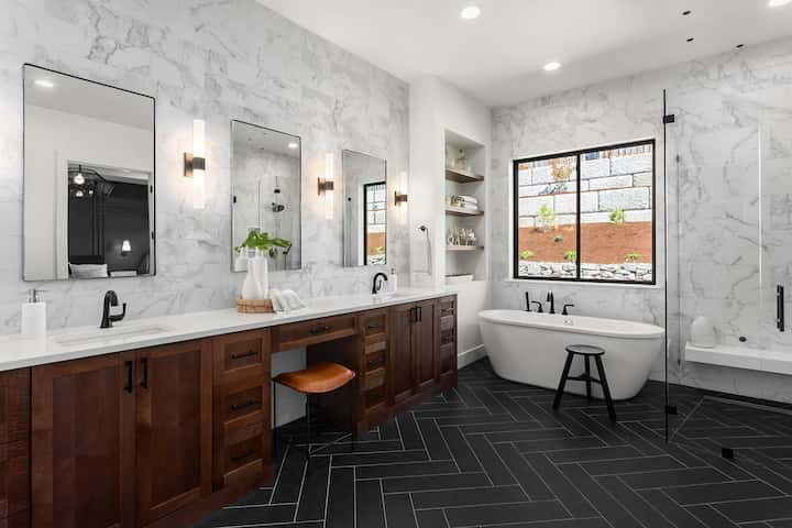 A complete bathroom remodel with wood cabinet sinks and free standing bathtub.